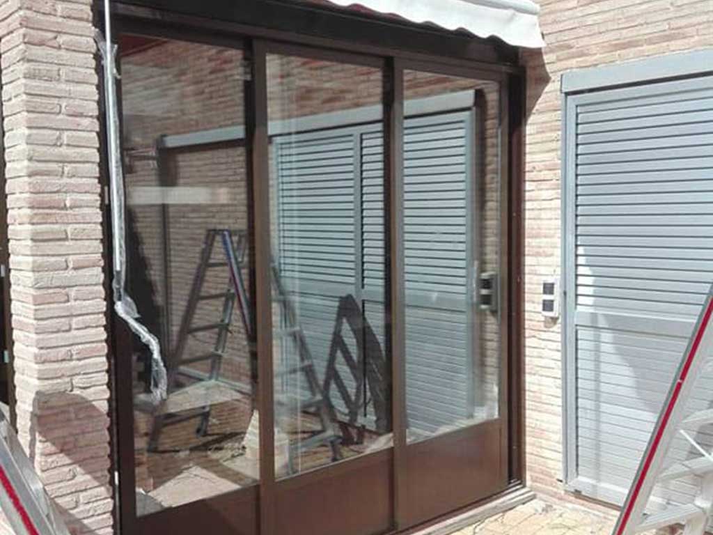 Instalación de puerta corredera de aluminio con cristal doble en acceso a terraza. Diseño moderno, con aislamiento térmico y acústico.