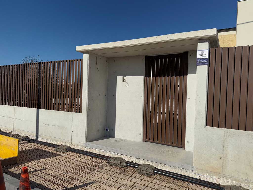 Instalación de puerta y vallado de lamas verticales en aluminio color madera. Diseño moderno para entrada de vivienda.