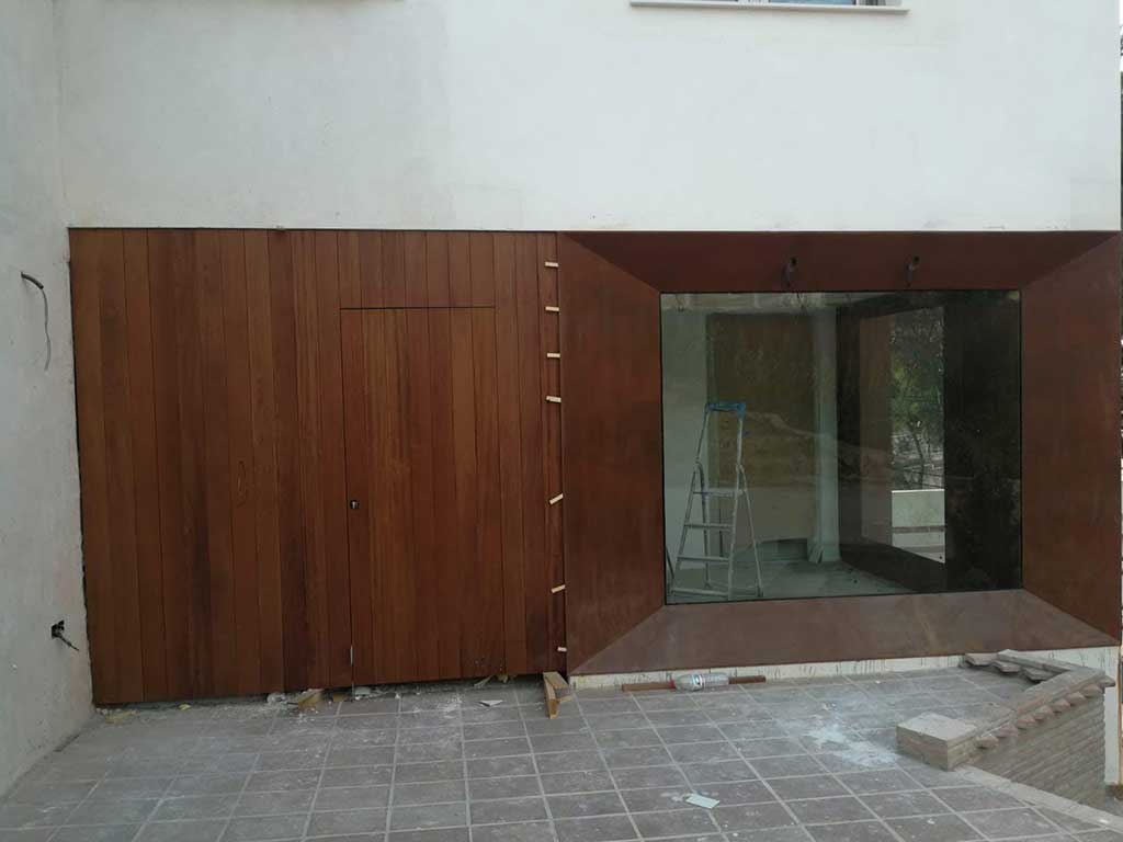 Revestimiento exterior de fachada en aluminio imitación madera con gran ventanal panorámico. Proyecto residencial moderno.
