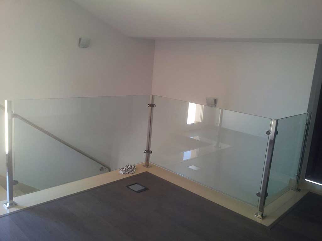 Barandilla interior de cristal con postes de acero inoxidable. Proyecto en vivienda moderna para escaleras y altillos.