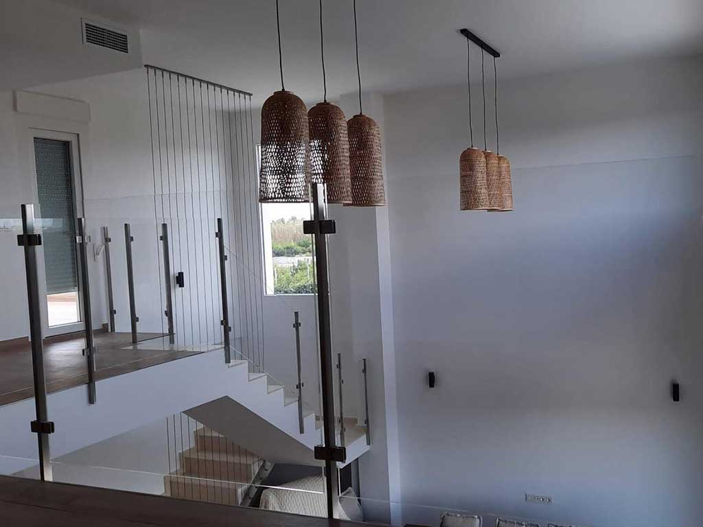 Barandilla de vidrio templado y acero en vivienda con doble altura. Seguridad y diseño en espacios interiores.